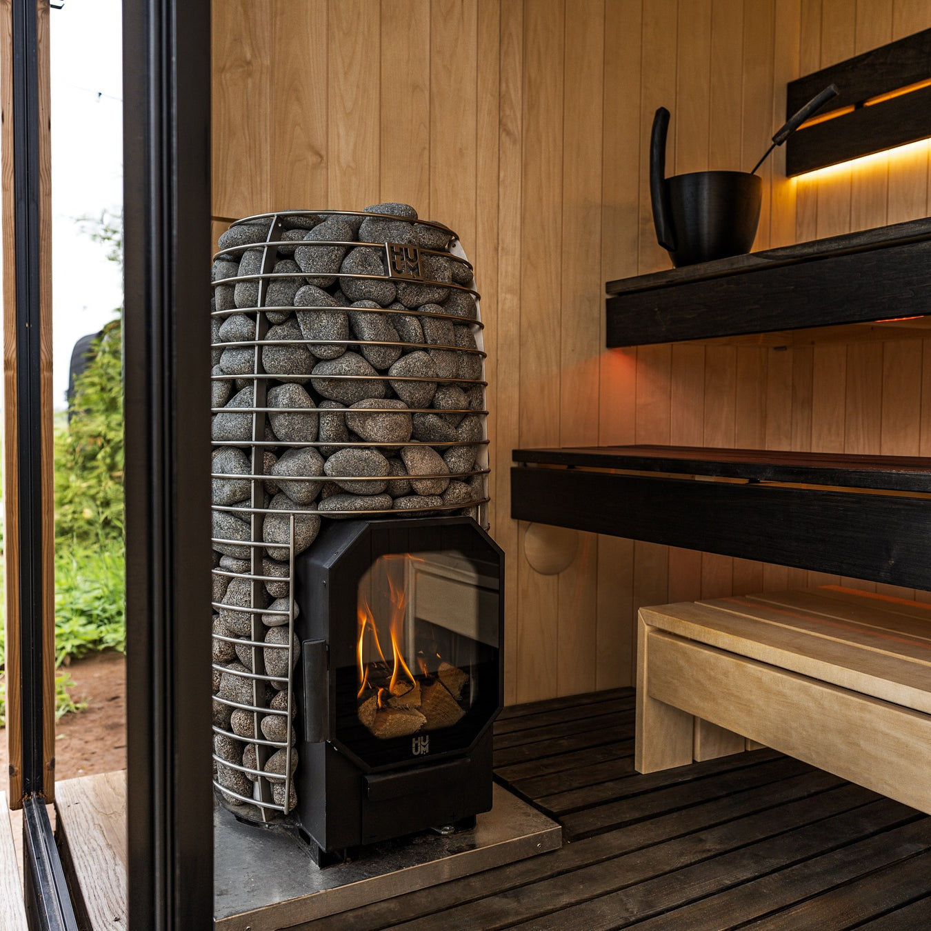 HUUM Wood Stove in Custom Sauna With Black Benches and Light Walls