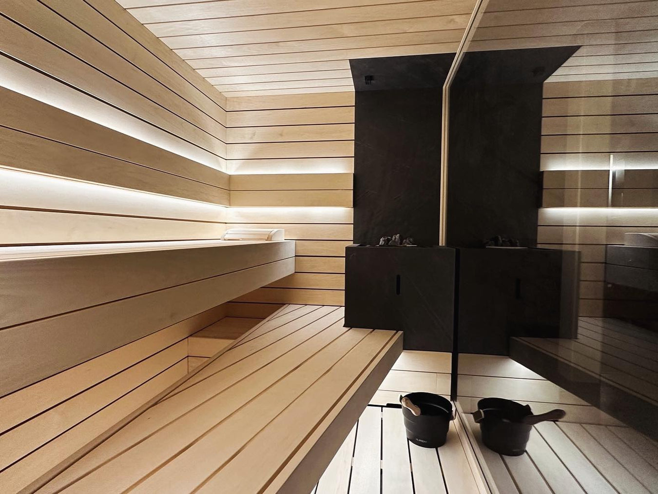 Interior of Light Custom Sauna With 2-Tier Benches and Black Heater